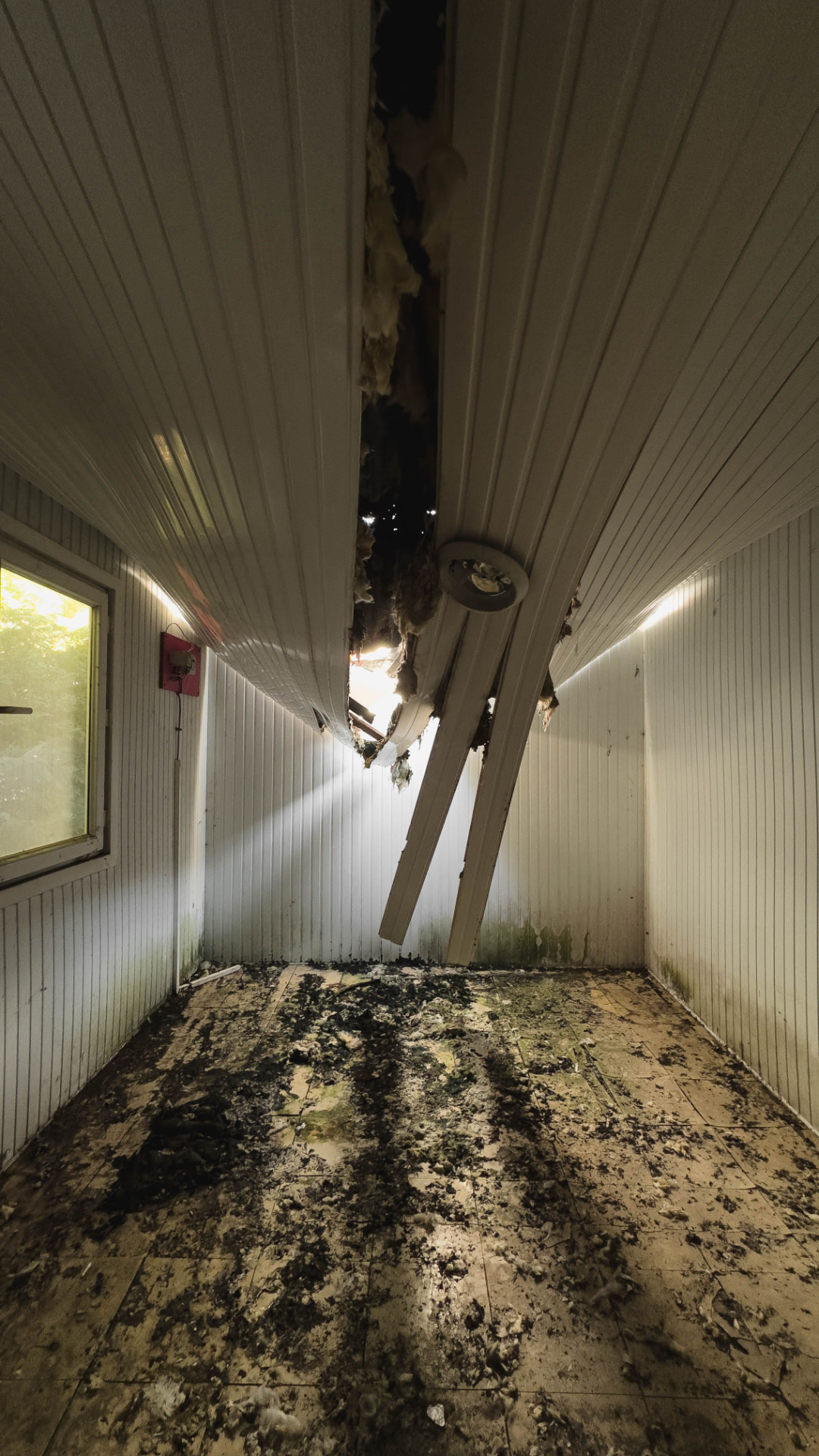Burned-out ceiling and soot-covered floor after a house fire